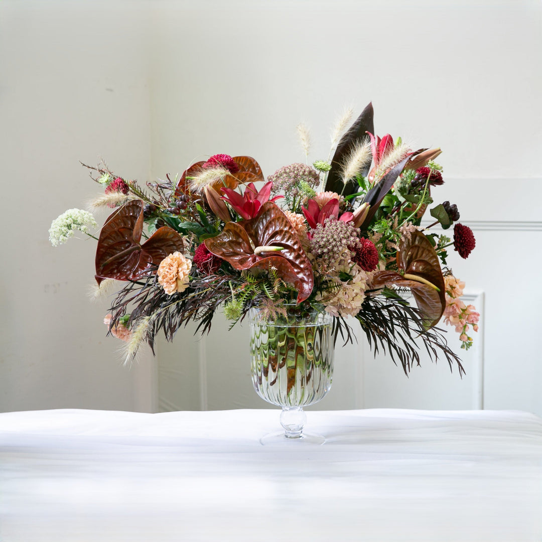 Colorful floral arrangement in a glass vase on a white surface with a white background