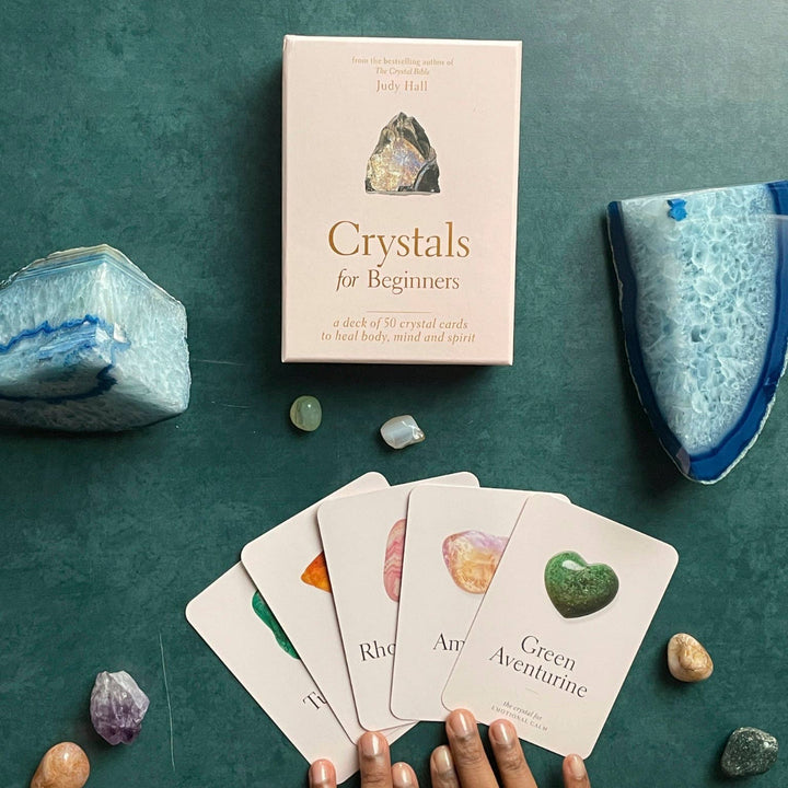 Card game set up with crystals and a book titled 'Crystals for Beginners' on a green surface.