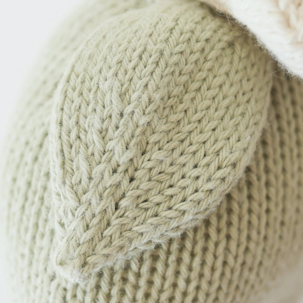 Close-up of a knitted beige fabric with a textured pattern on a light background