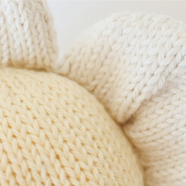 Close-up of three cream-colored yarn balls on a light background