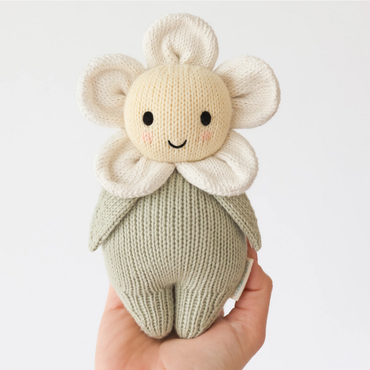 Knitted toy resembling a flower held in a hand against a light background