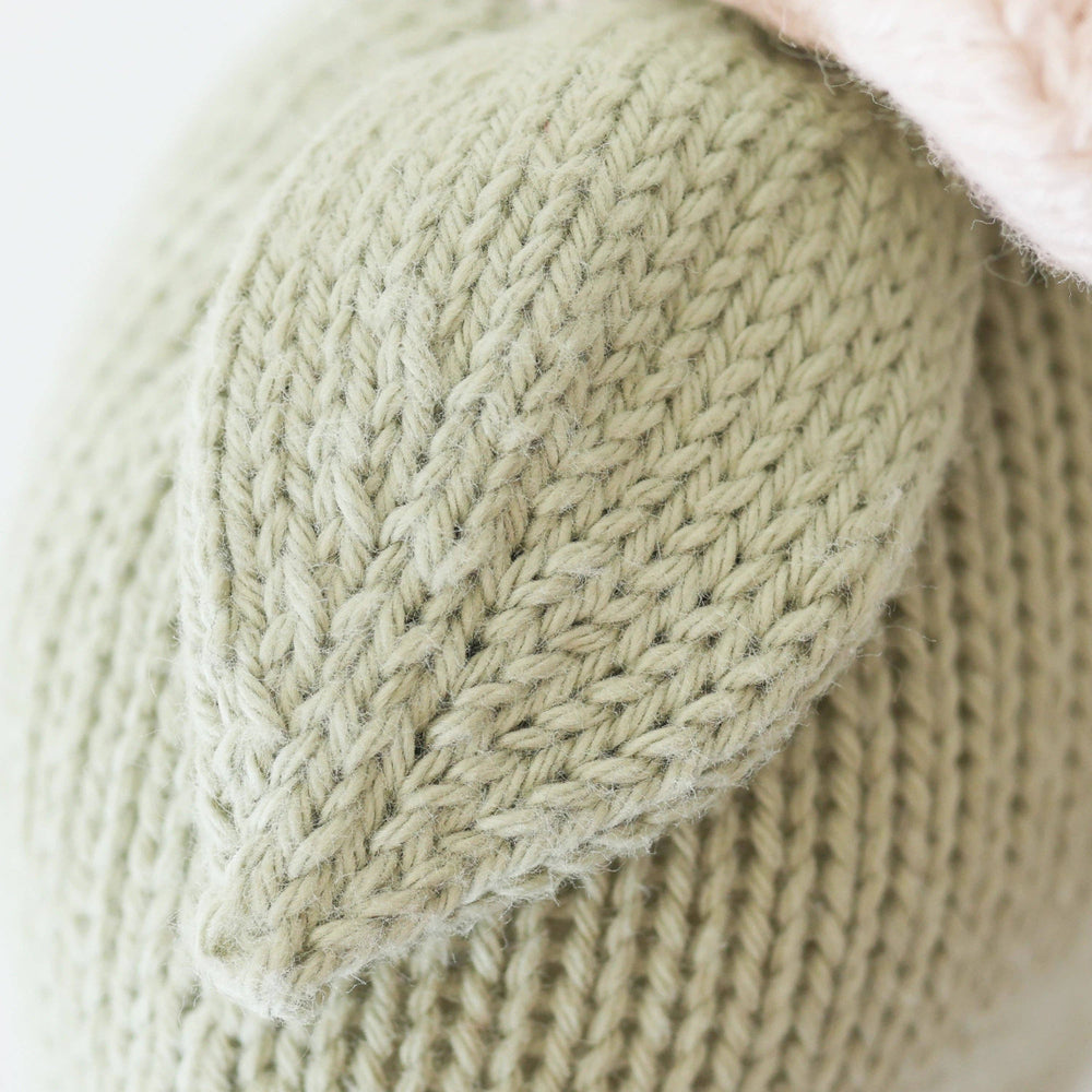 Close-up of a knitted green fabric with a textured pattern on a light background