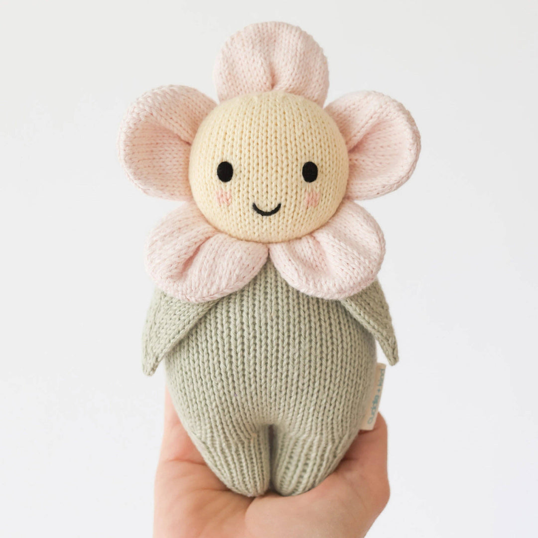 Knitted flower-shaped toy held in a hand against a white background