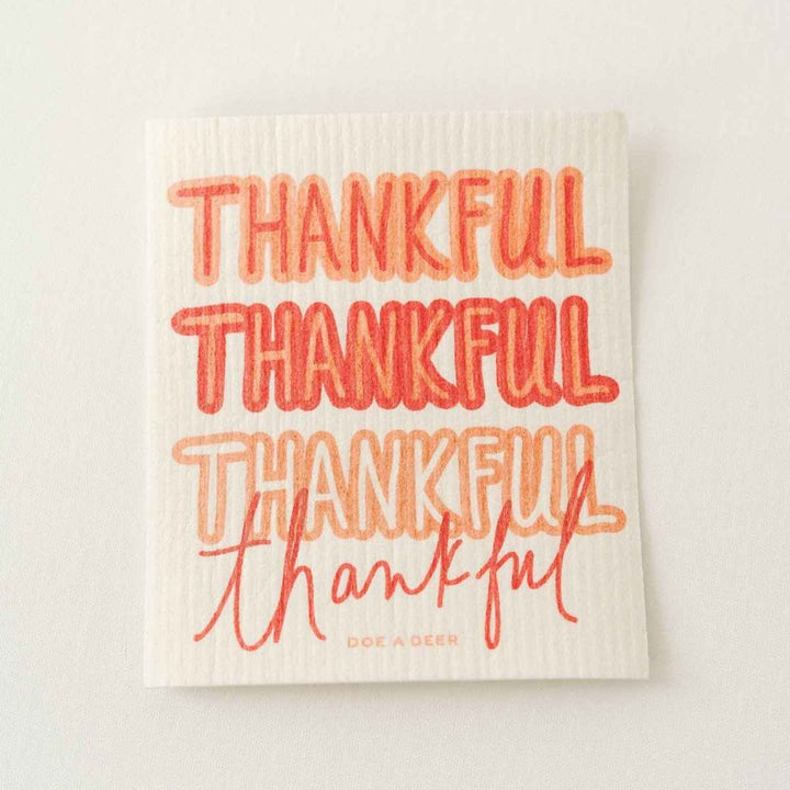 Doe A Deer | Thankful Swedish Dishcloth | a white cloth with orange text that reads "Thankful thankful thankful thankful".