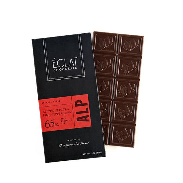 A bar of chocolate with its black packaging box, featuring a red label that reads &