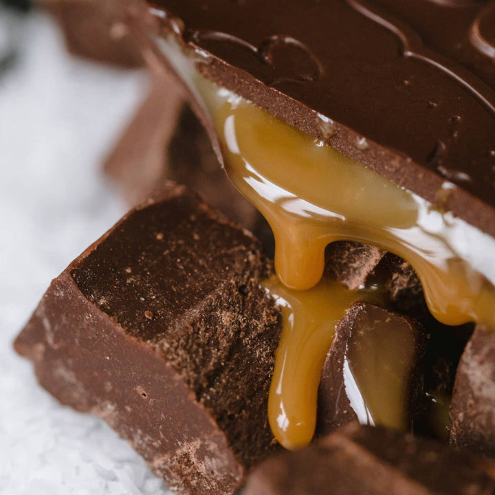 Close-up of chocolate bars with caramel drizzle on a white surface