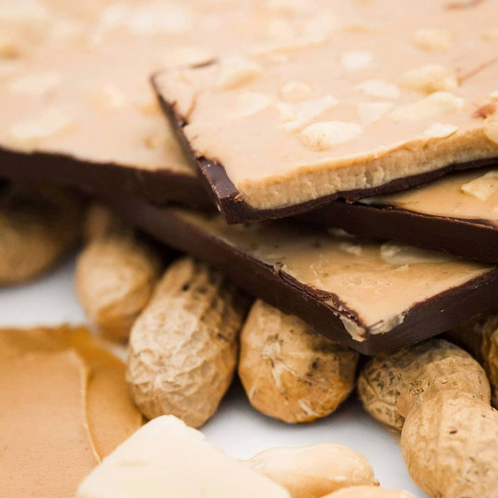 Ethereal Confections | Close-up of a stack of chocolate-covered peanut butter bars with peanuts in the shell.