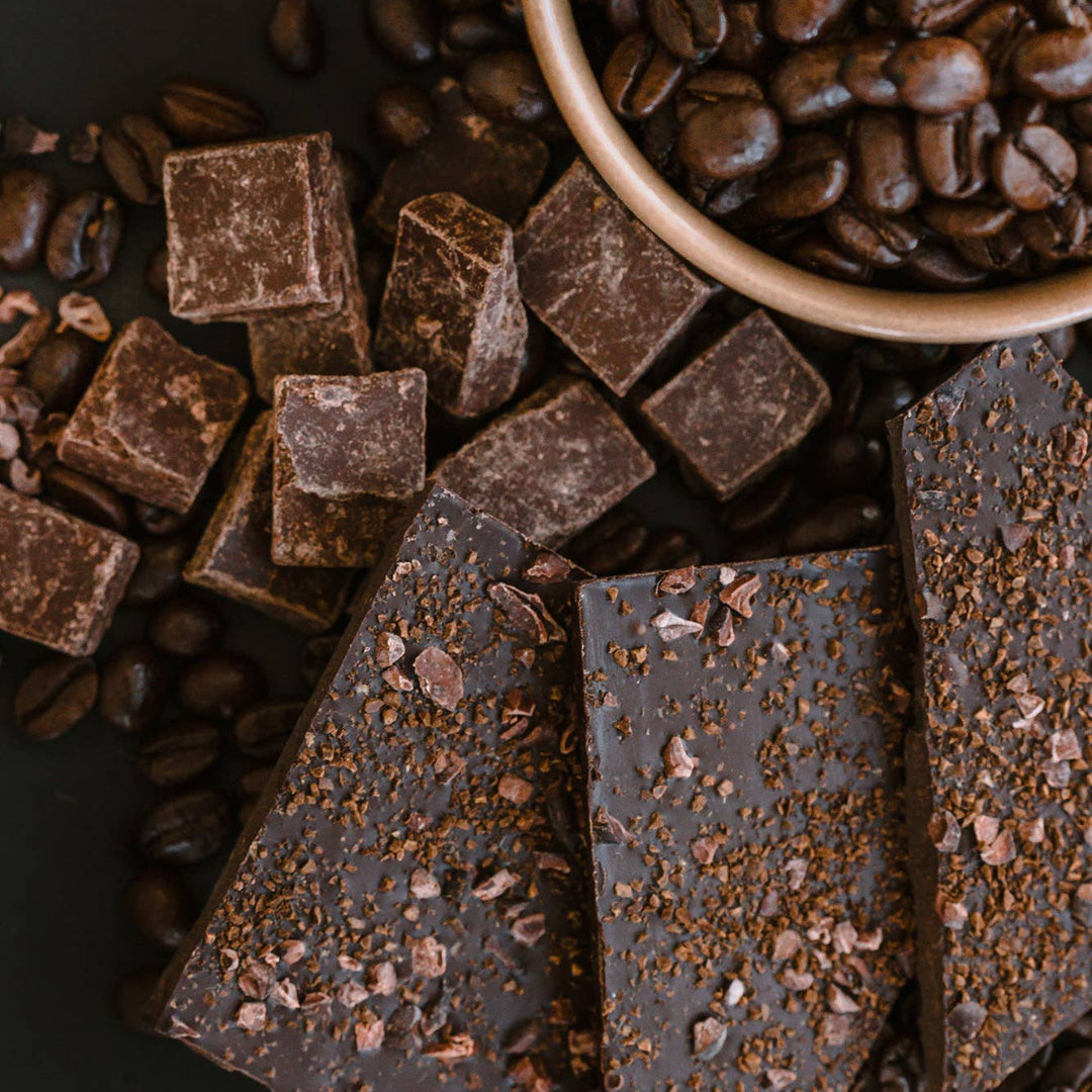 Dark chocolate bars with coffee beans on a dark surface