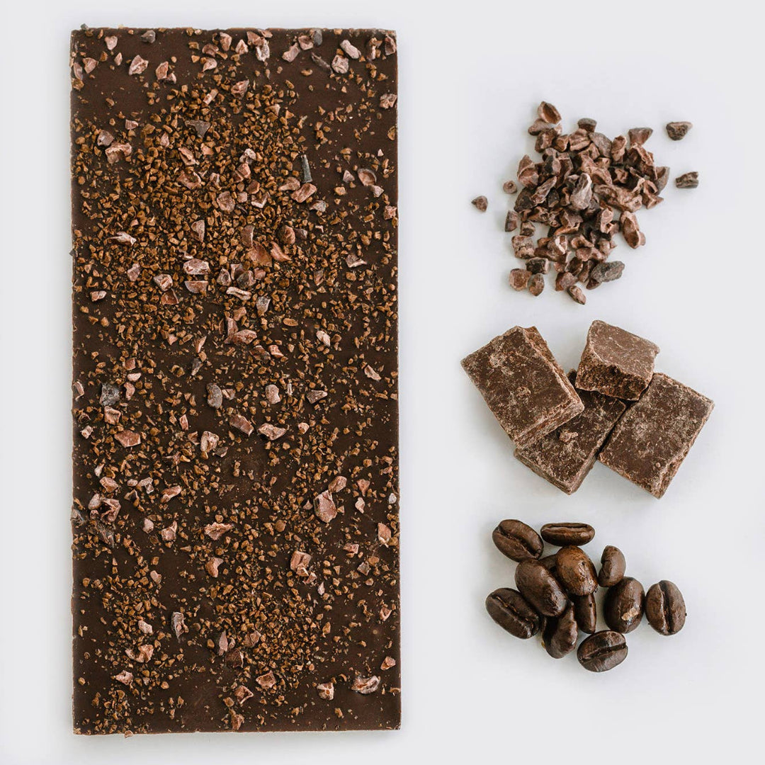Dark chocolate bar with cacao nibs and coffee beans on a white background