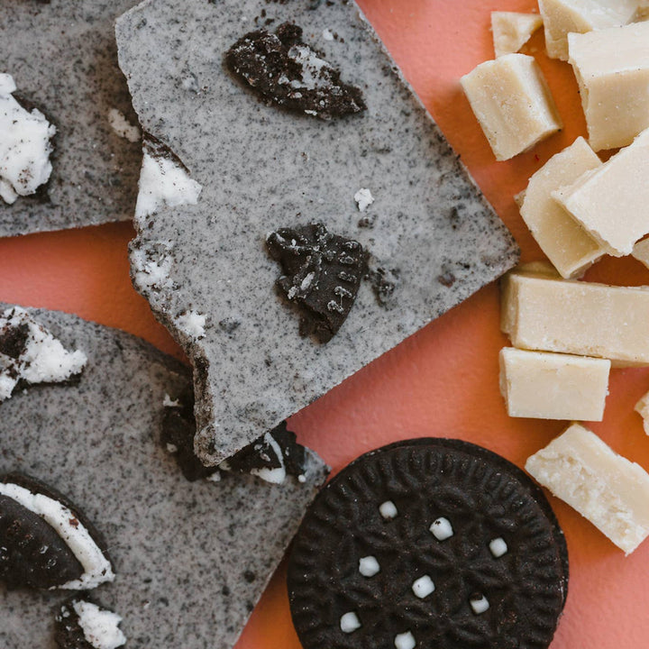 Oreo cookies and cookie dough pieces on a pink surface