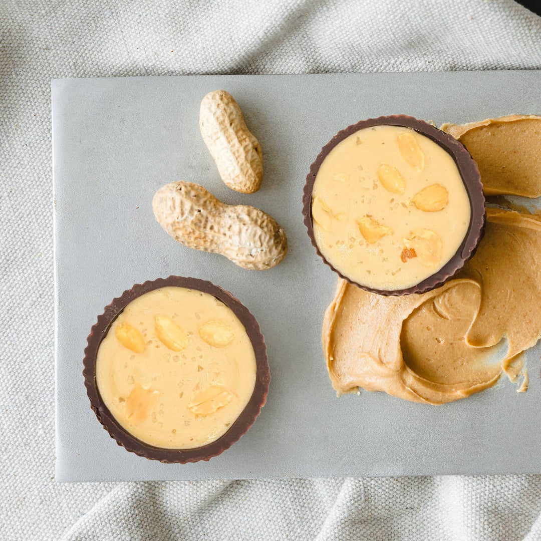 Peanut butter cups on a marble slab with peanuts