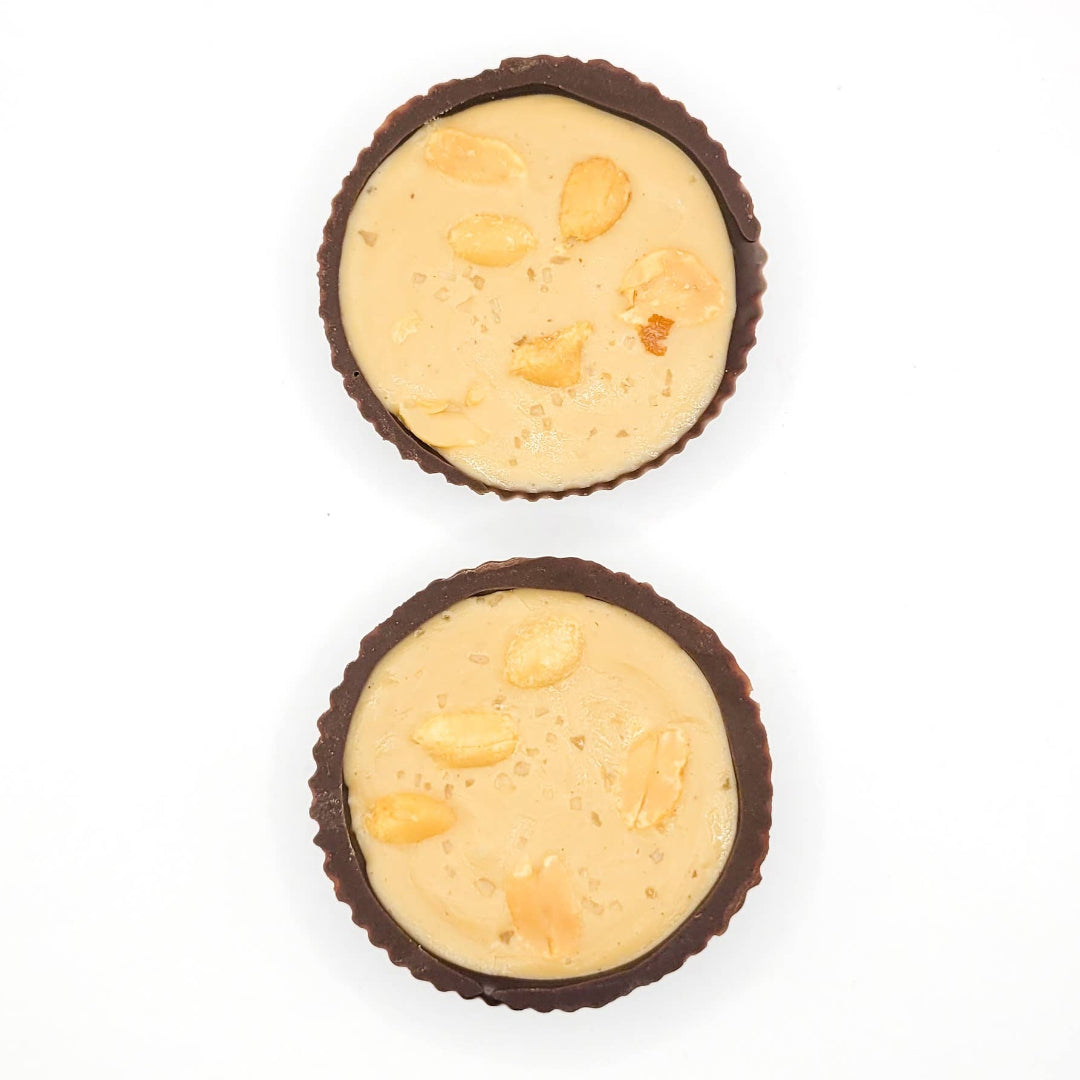 Two chocolate cups filled with a creamy peanut butter filling on a white background