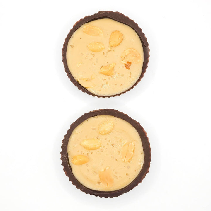 Two chocolate cups filled with a creamy peanut butter filling on a white background