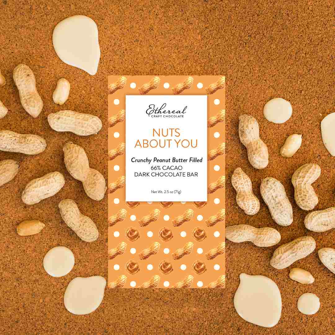 Ethereal Confections | Chocolate bar packaging with peanuts on a brown background. Crunchy peanut butter filled. 66% cacao, dark chocolate bar.