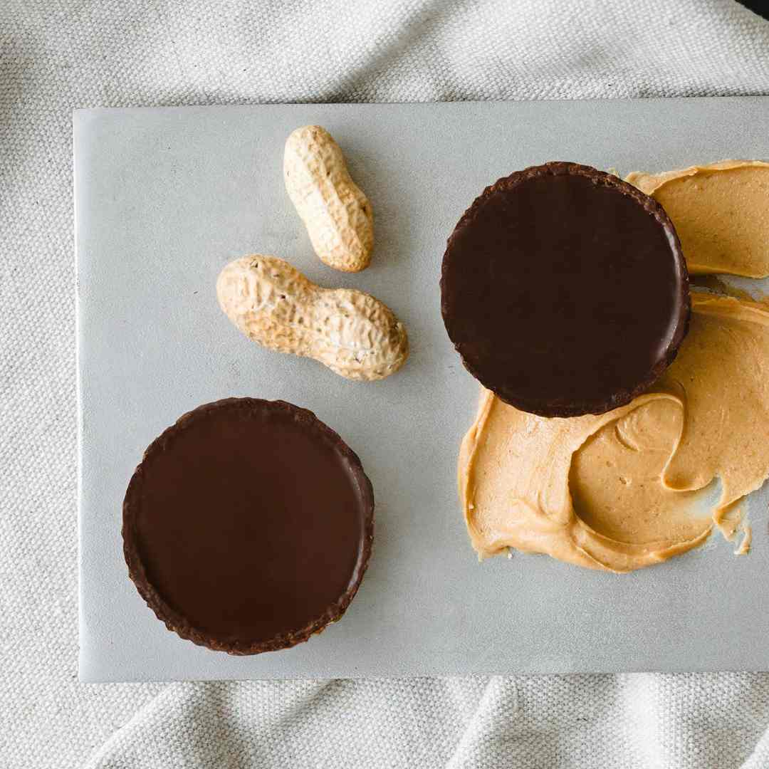 Ethereal Confections | Two chocolate-covered peanut butter cups on a marble surface with a light fabric background.