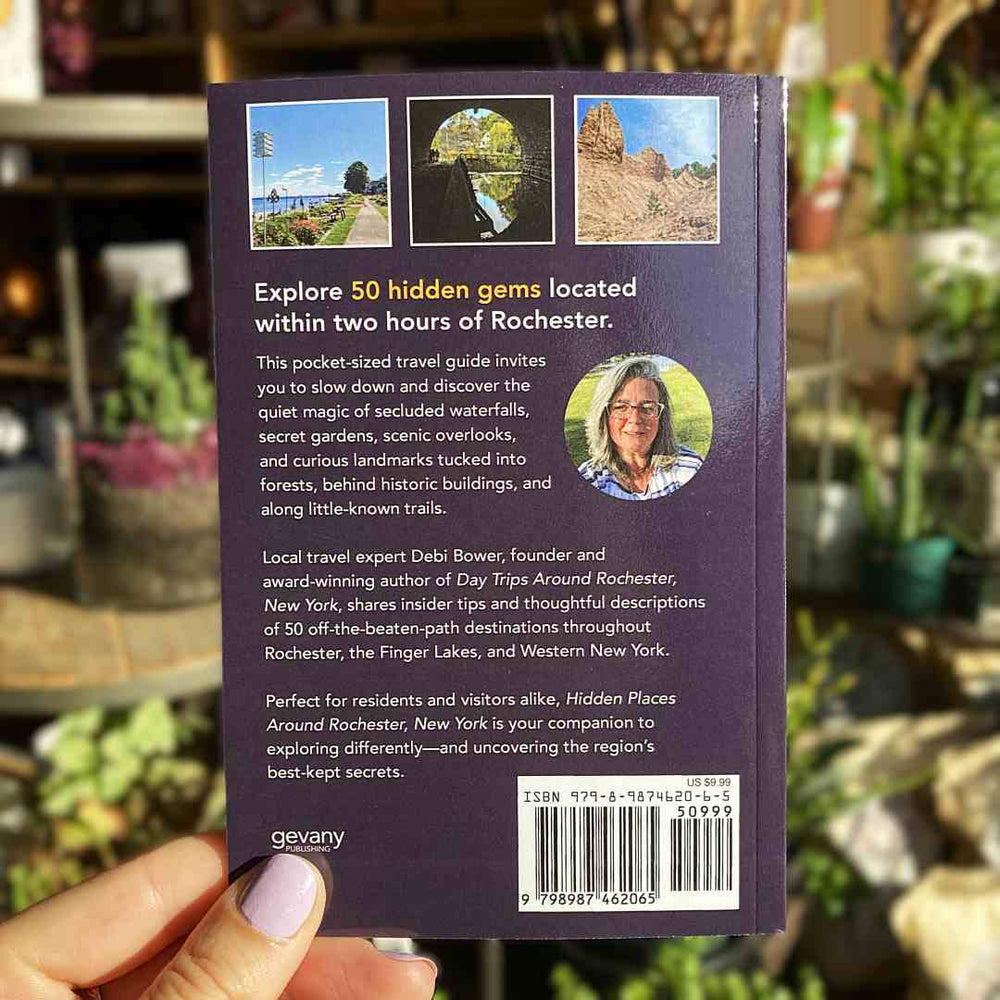 Stacy K Floral | Debi Bower | Back cover of a travel guidebook held by a hand with a blurred background full of plants.