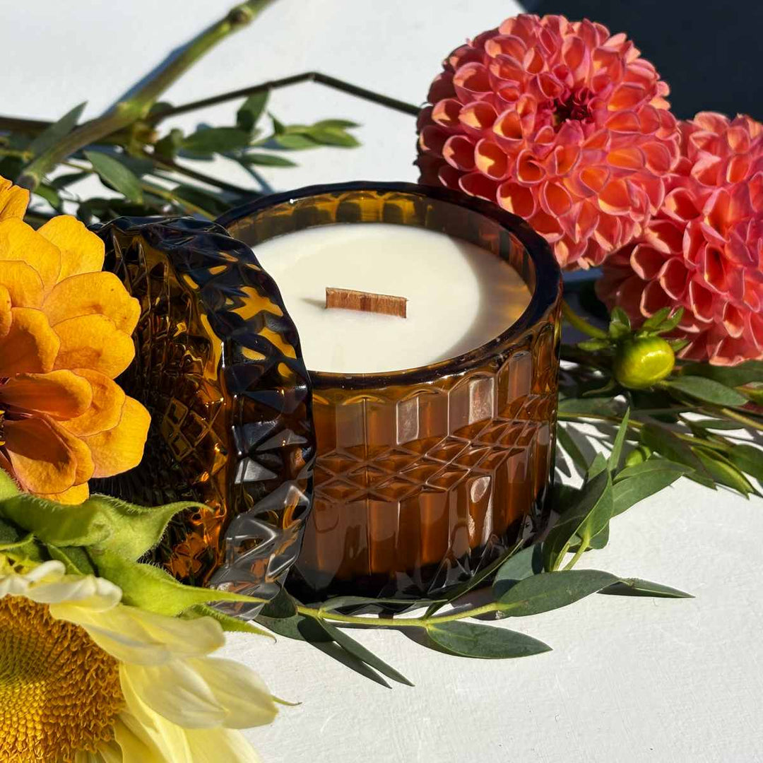 Stacy K Floral | Fleurish Co | Fall Foliage | Candle in a decorative glass holder surrounded by flowers on a white background.