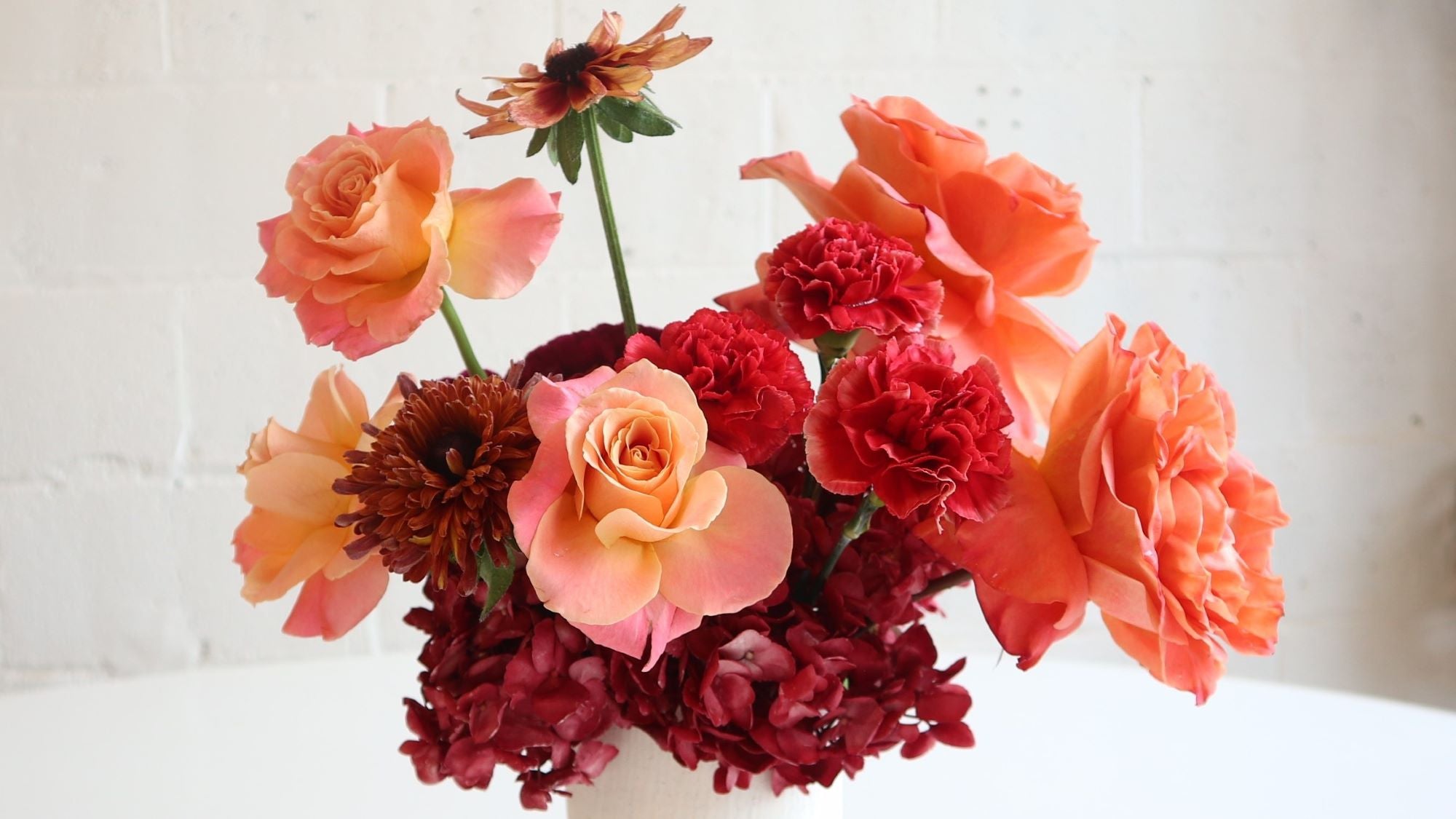 Orange and red fall arrangement of mums roses and dahlias at Stacy K Floral