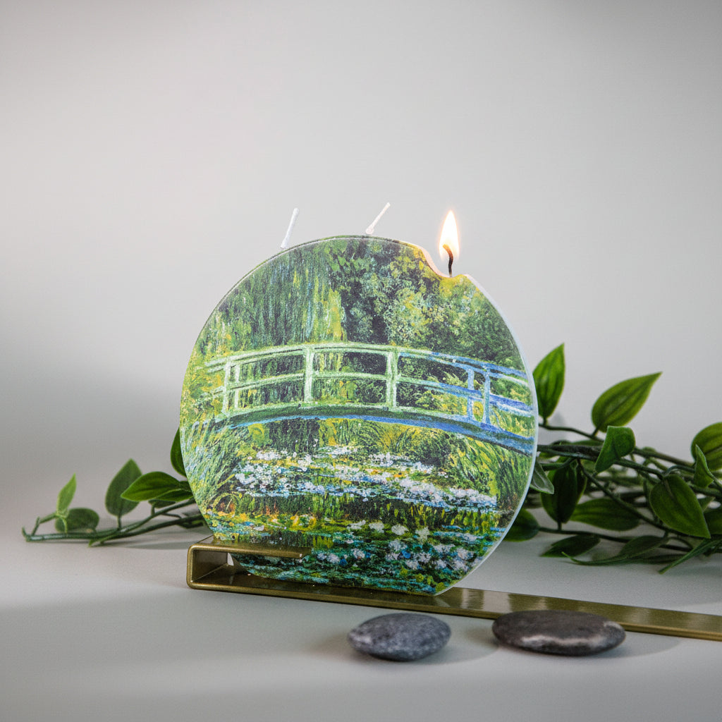 Candle with a design of a bridge over water lilies on a white background