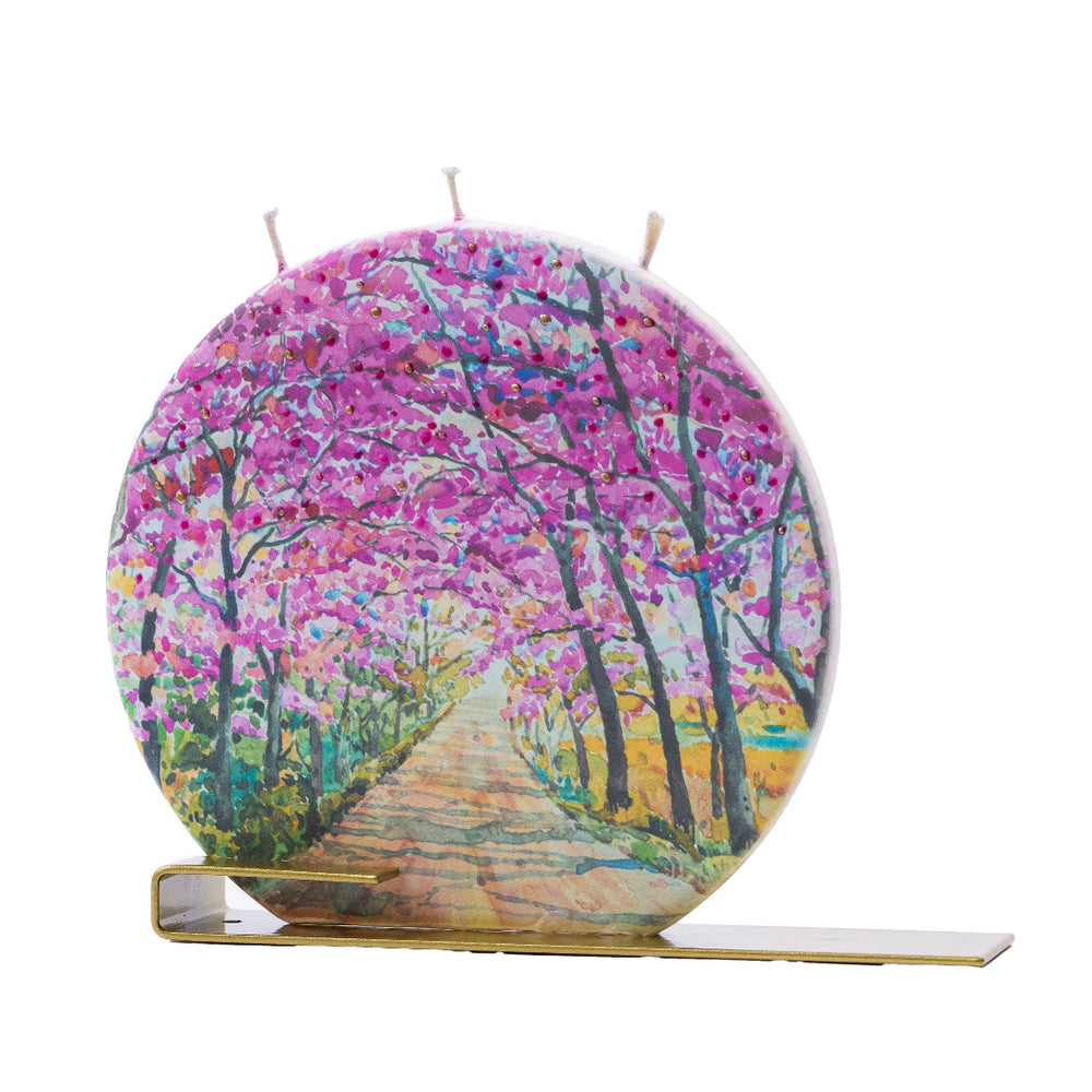Circular candle with a nature-themed design on a white background