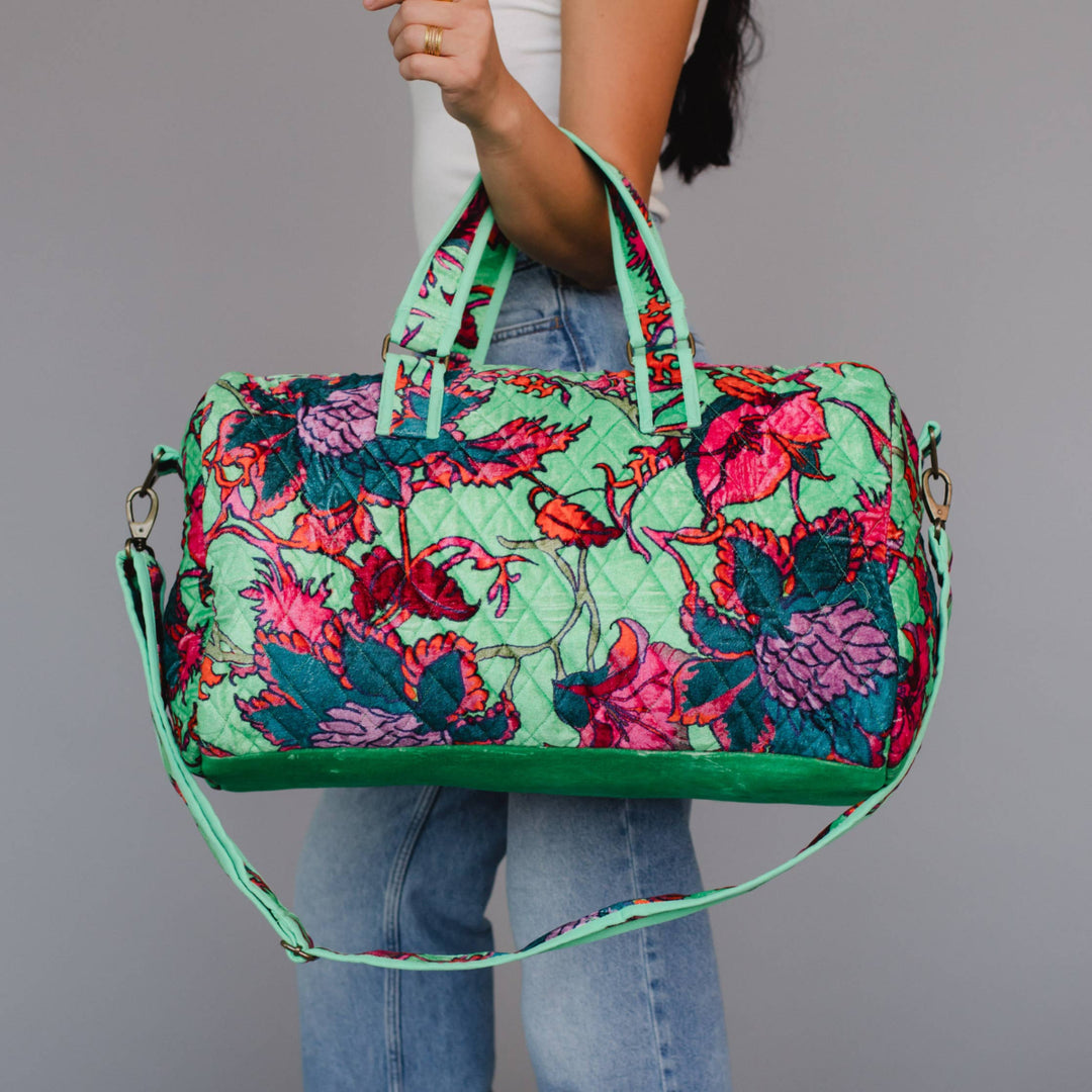 Person holding a colorful floral-patterned bag against a gray background