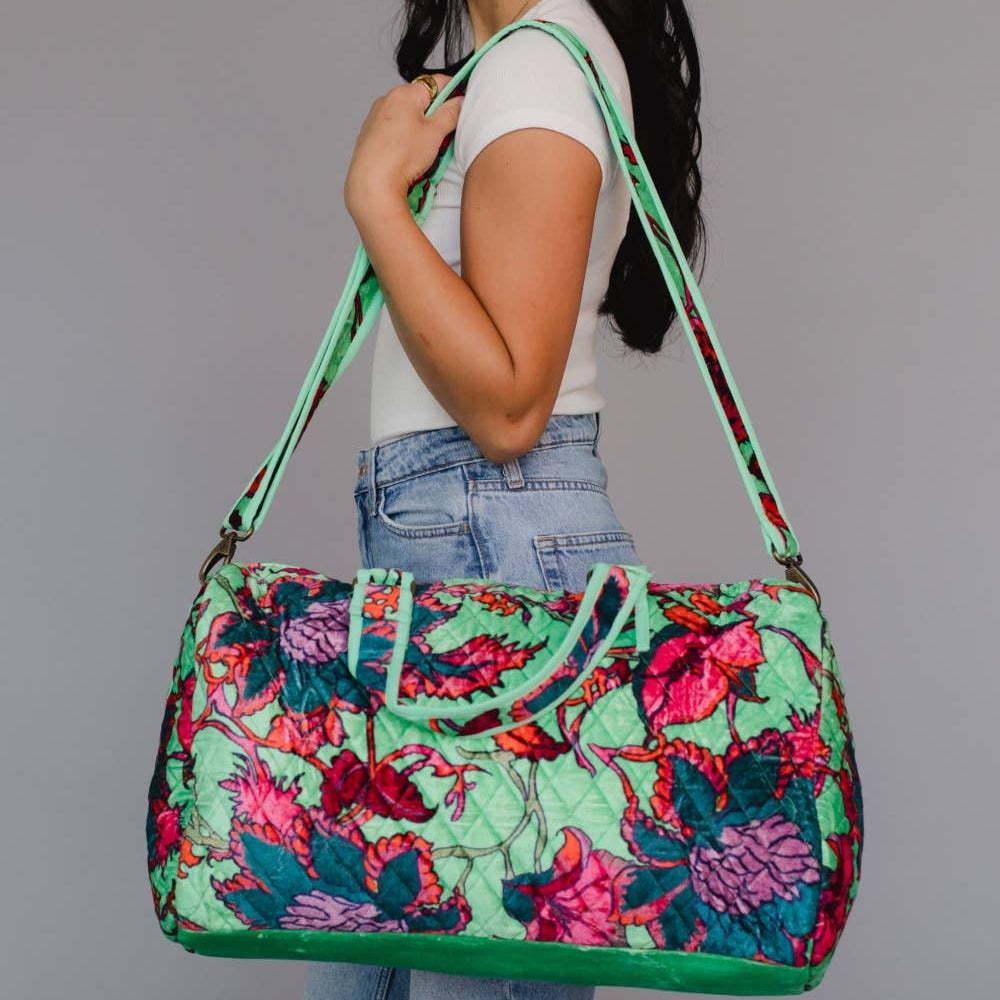 Woman holding a colorful floral-patterned bag against a plain background