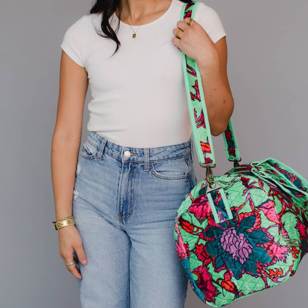 Person holding a colorful floral-patterned bag against a gray background