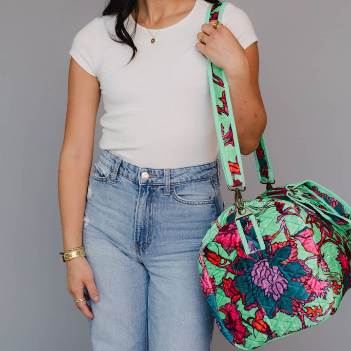 Person holding a colorful floral-patterned bag against a gray background