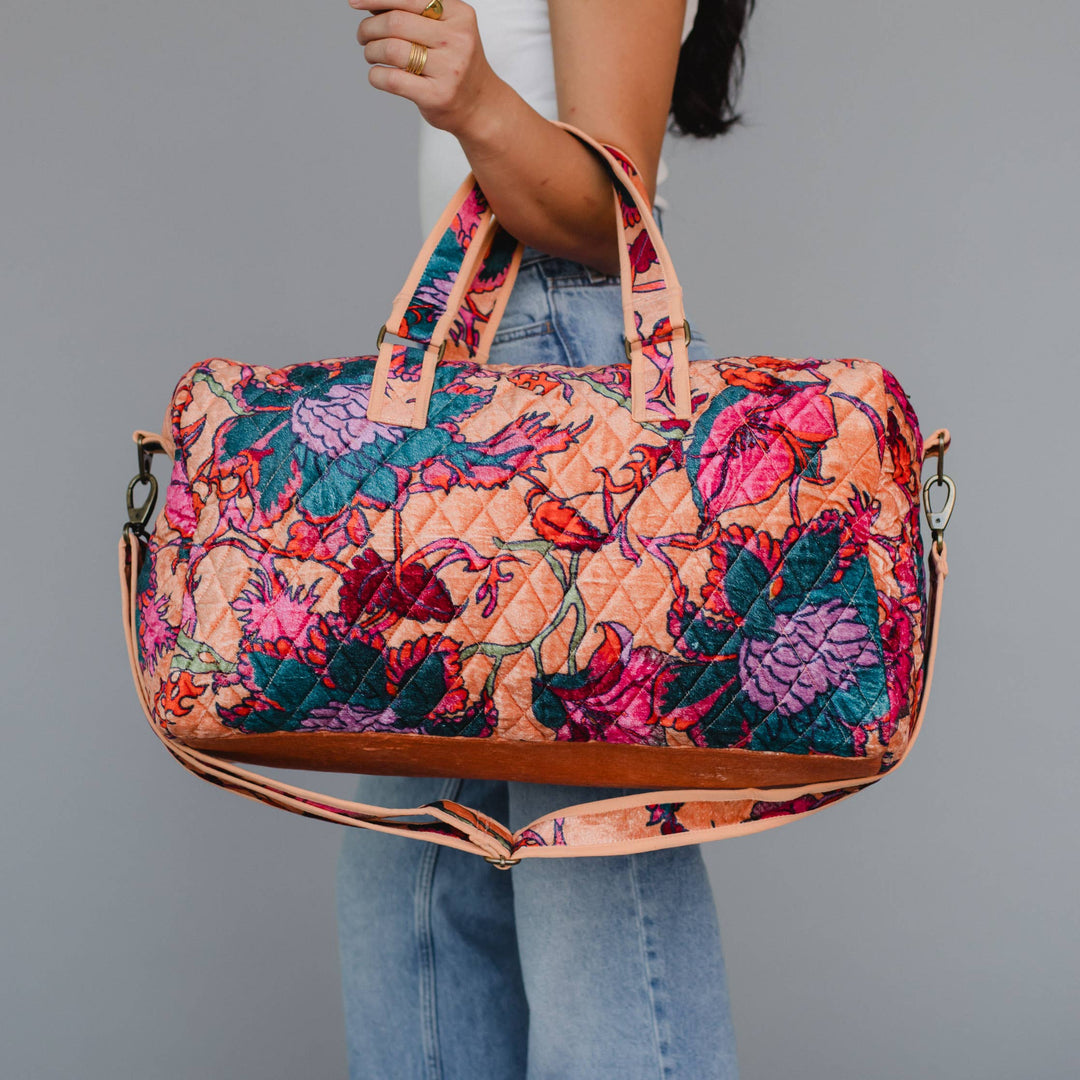 Floral patterned bag held by a person against a gray background