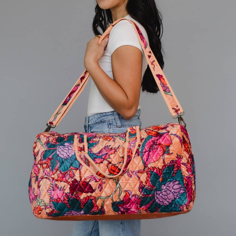 Woman holding a colorful floral-patterned bag against a gray background