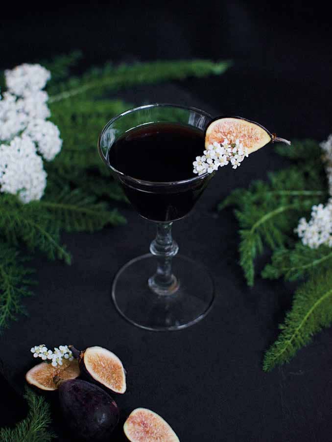 National Book Network | Flower-Infused Cocktail: Flowers, with a Twist | A dark brown cocktail with tiny flowers, greenery, and figs as a garnish.