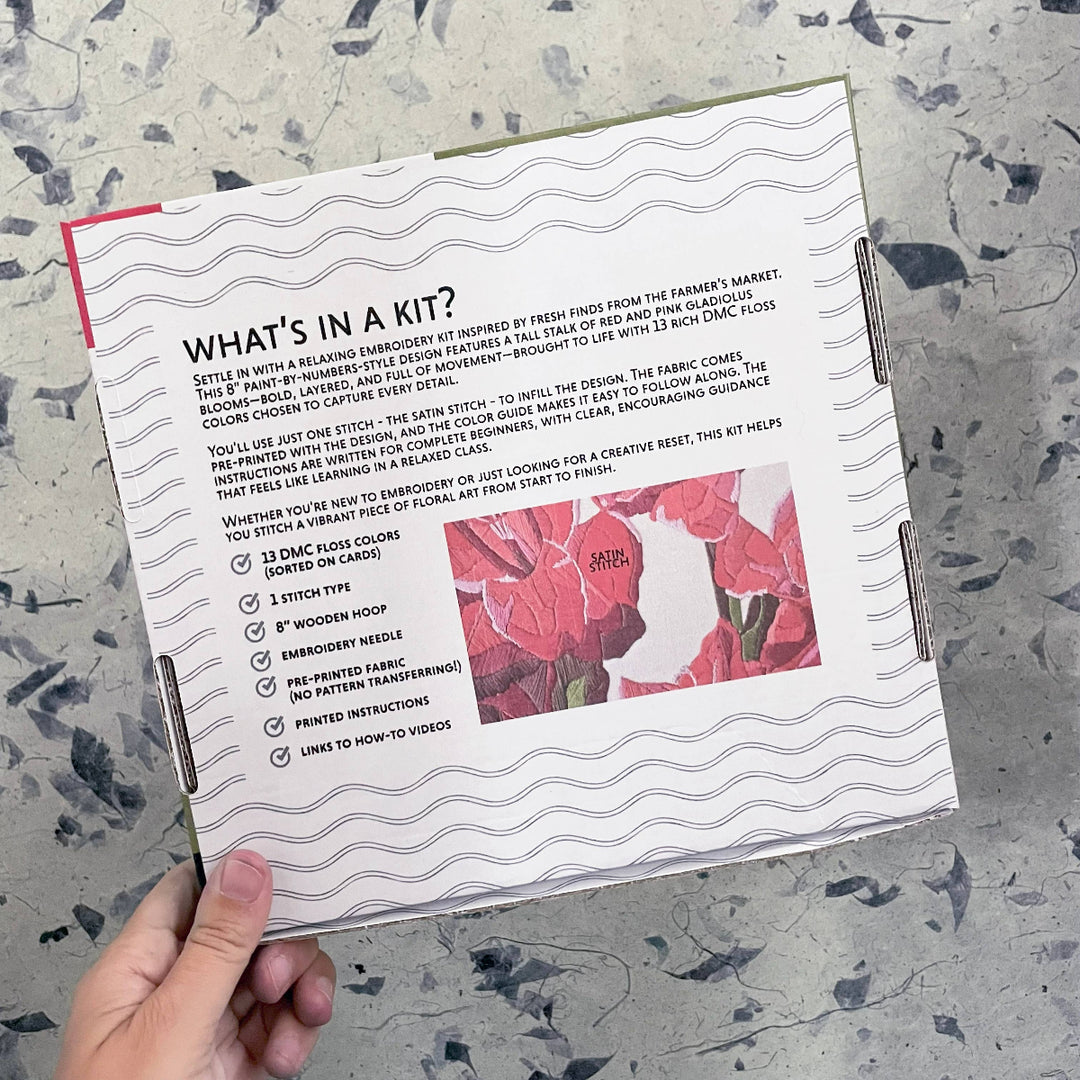 Embroidery kit packaging with text and floral design on a textured surface