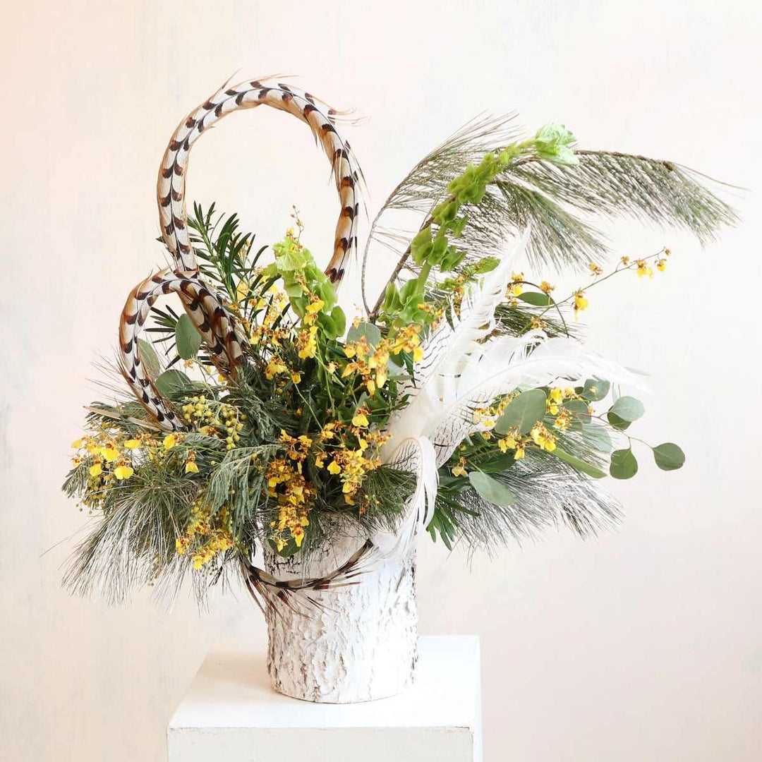 Stacy K Floral | Golden Woodland Floral Arrangement | A white birch vase with feathers, orchids, and a range of greenery.