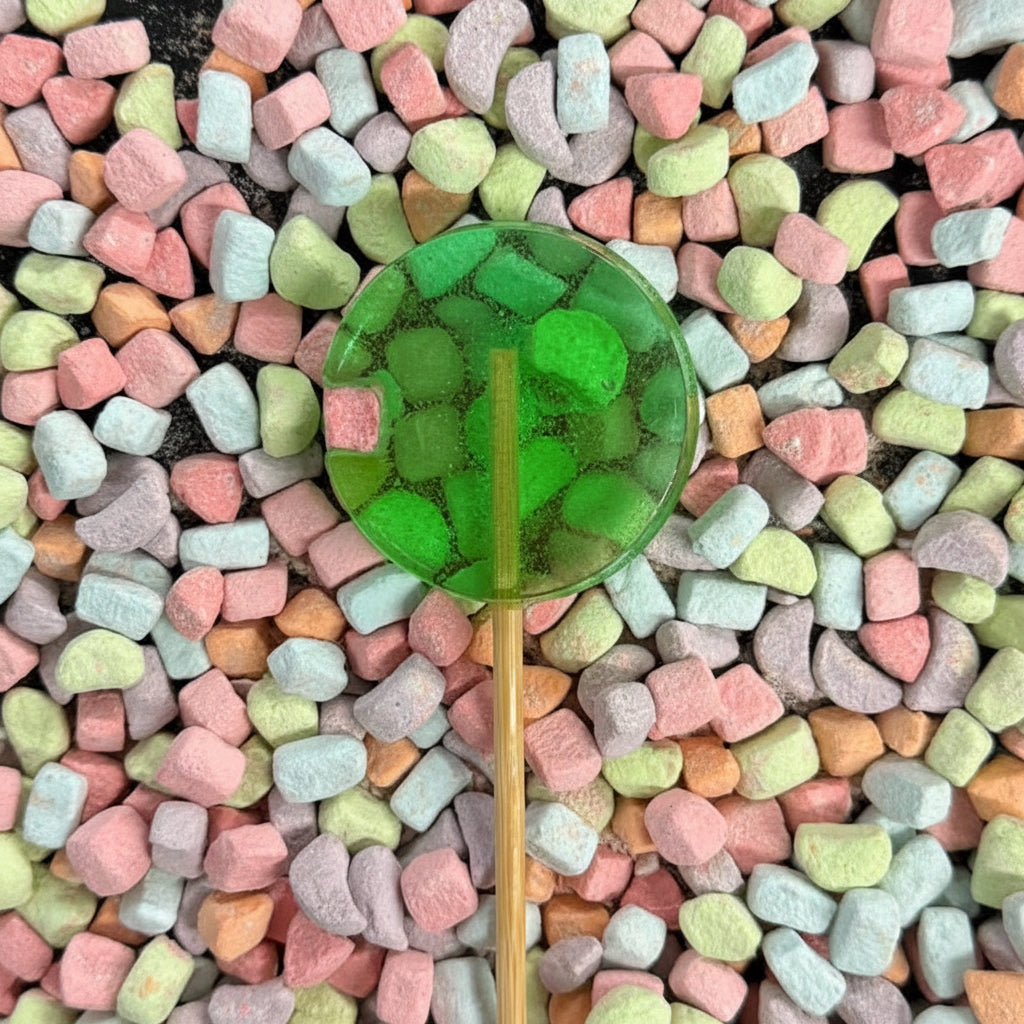 Pastel-colored candy pieces arranged in a circular pattern on a black surface with a green leaf in the center.