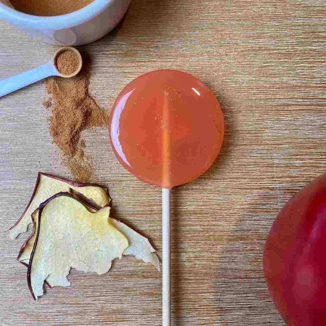 Good Lolli | Apple Cider Lollipop | A lollipop next to dried apple peels and  cinnamon.