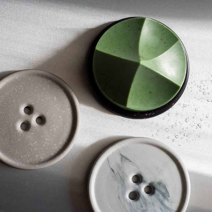 Three ceramic buttons with different designs on a light surface
