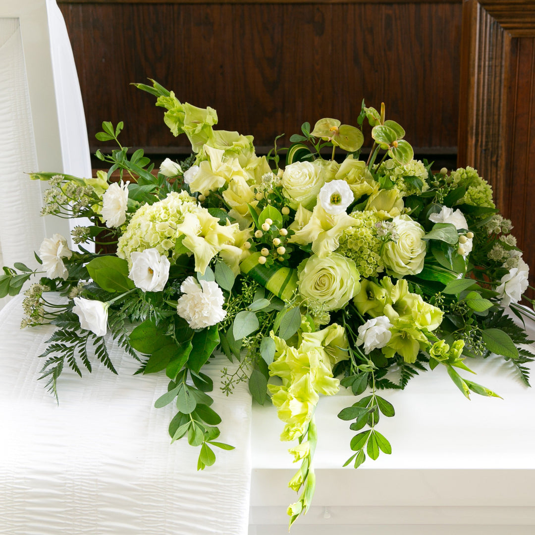 Casket floral arrangement with green and white flowers.