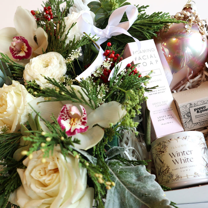 Sparkling Winter Gift Box | Close up on the floral arrangement, foaming facial soap, illume winter white candle, poppy & pout marshmallow creme lip scrub, and pink ornament.