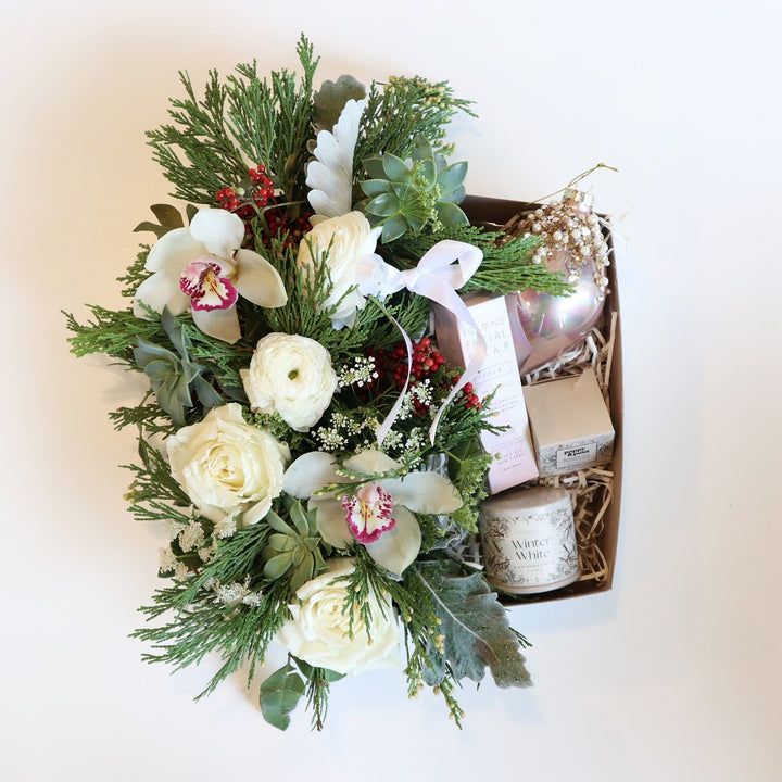 Sparkling Winter Gift Box | A classic whites and greens arrangement with red accents. Gift box comes with fresh flora, a candle, lip scrub, an ornament, and foaming facial soap.