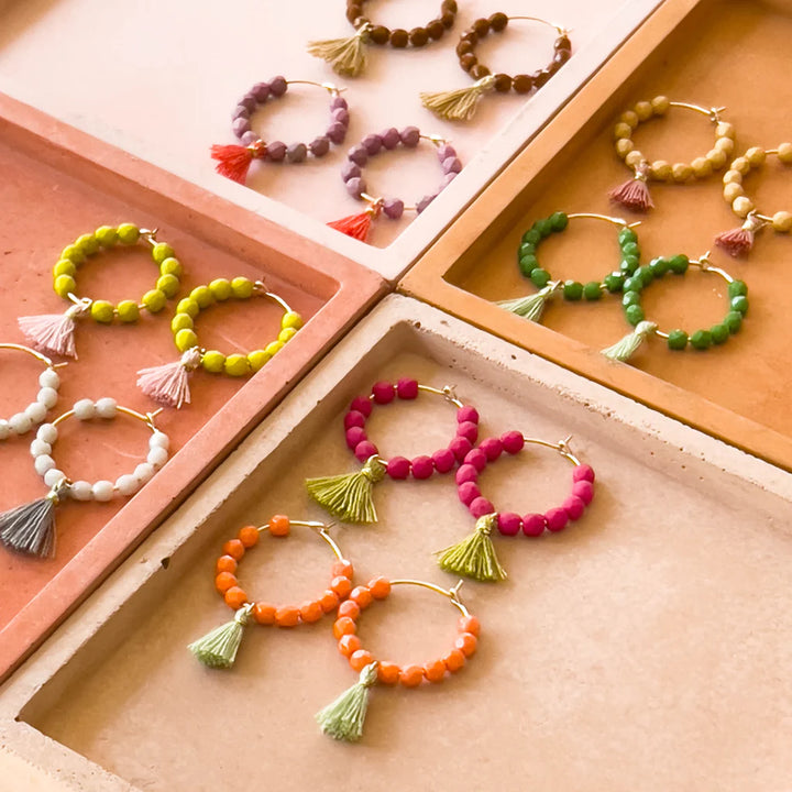 Small Gold Hoops with Beads and Tassels | Multiple colors of beaded earrings displayed in 4 small boxes. Colors are white/gray, lime/pink, purple/red, brown/caramel, caramel/pink, green/lime, magenta/green, and orange/lime.