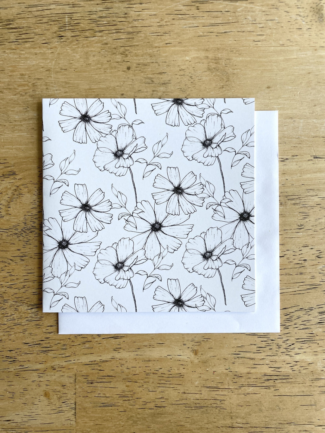 Square white greeting card showcase illustrations of black and white cosmo blooms in a delightful pattern.