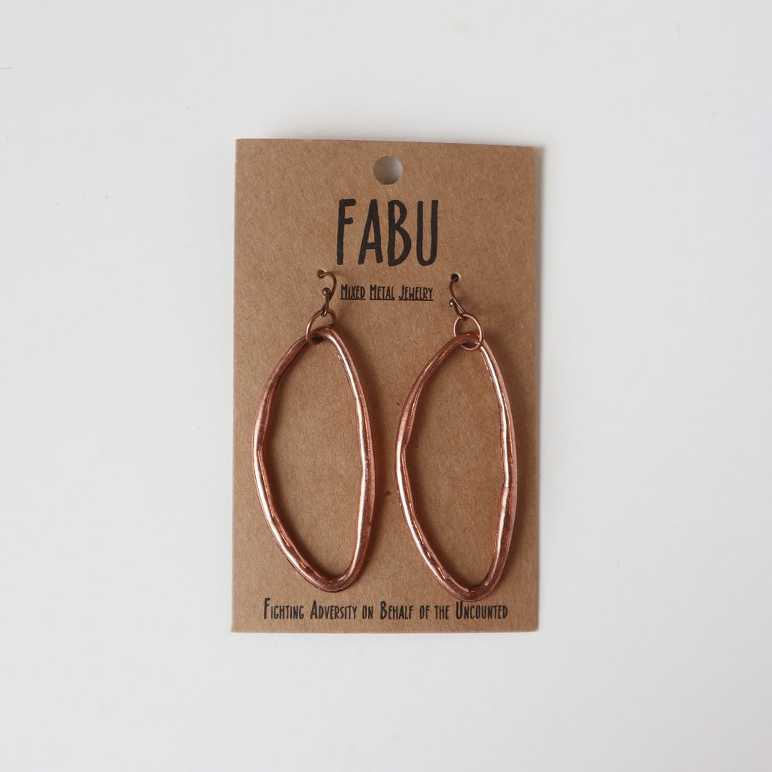 Fabu Earrings | Copper earrings that are "flattened" loops in a more of an oval shape.  On a brown paper backing. Reads "Fabu, mixed metal jewelry, Fighting Adversity on Behalf of the Uncounted".