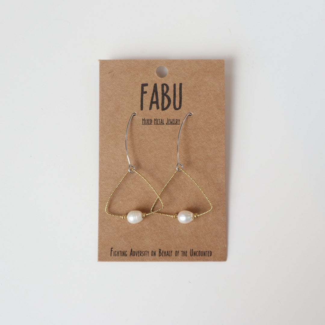 Fabu Earrings | A gold wire earring shaped like a triangle that has a pearl bead at the bottom.  On a brown paper backing. Reads "Fabu, mixed metal jewelry, Fighting Adversity on Behalf of the Uncounted".