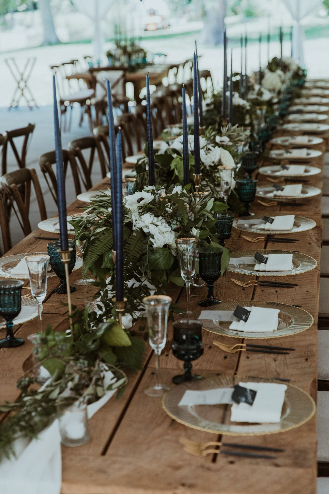 Navy blue tapers candles on a farm table with greenery at the Inns of aurora