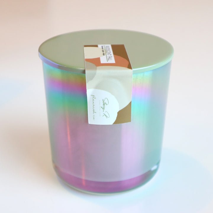 Iridescent Fall | An iridescent candle with purple, pink, green, blue, and yellow. Held shut with a fall colored sticker/label that reads "Iridescent Fall, Geranium, Apple, Maple, Stacy K Floral and Fleurish Co."