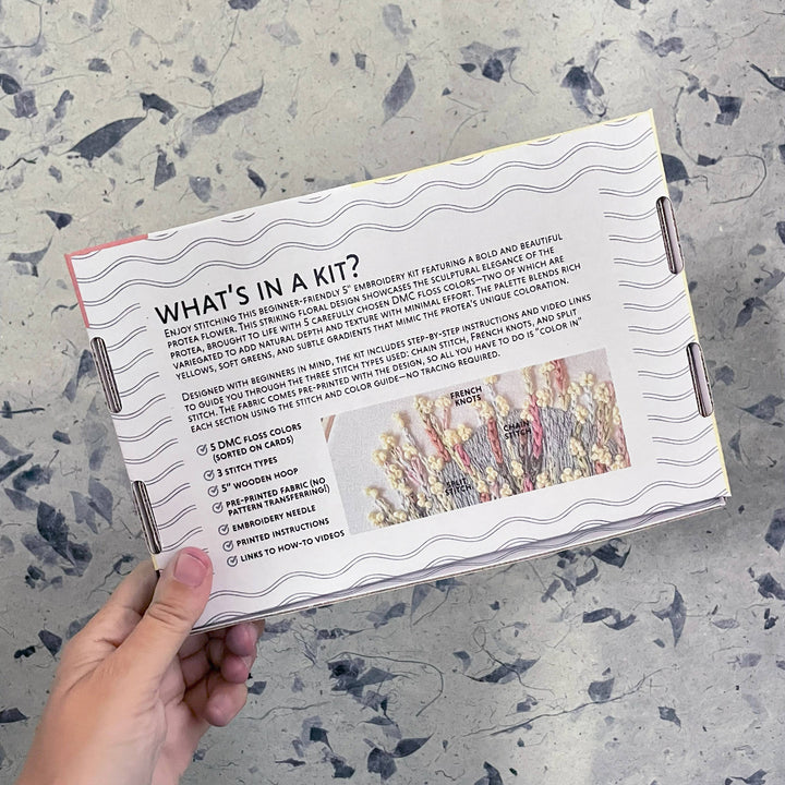 Hand holding a craft kit with instructions on a textured surface