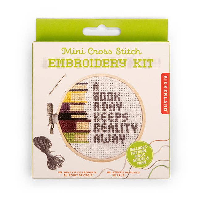 Kikkerland | Kikkerland Mini Cross Stitch Embroidery Kit packaging with text 'A Book A Day Keeps Reality Away'.