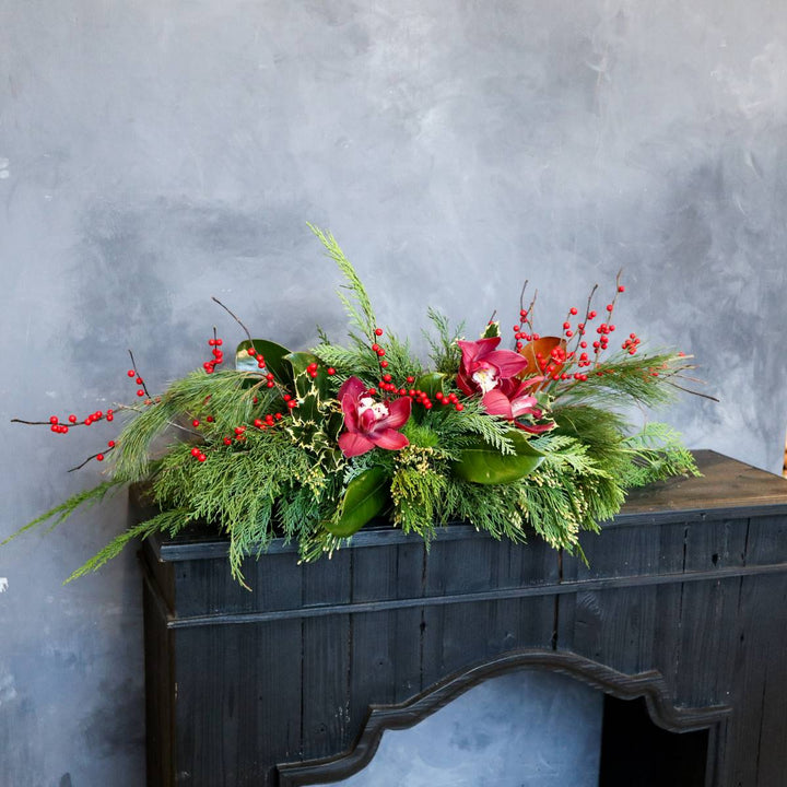 Stacy K Floral | Christmas Centerpiece, long and low with evergreens, red berries, and red orchids.