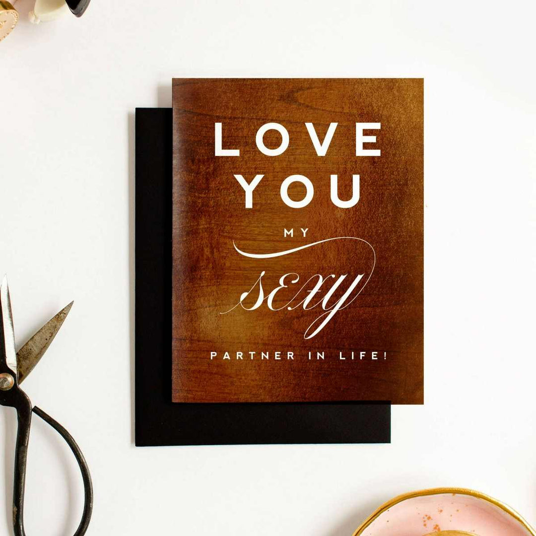 A wood patterned card with the title "Love you my sexy partner in life!". Comes with a black envelope.