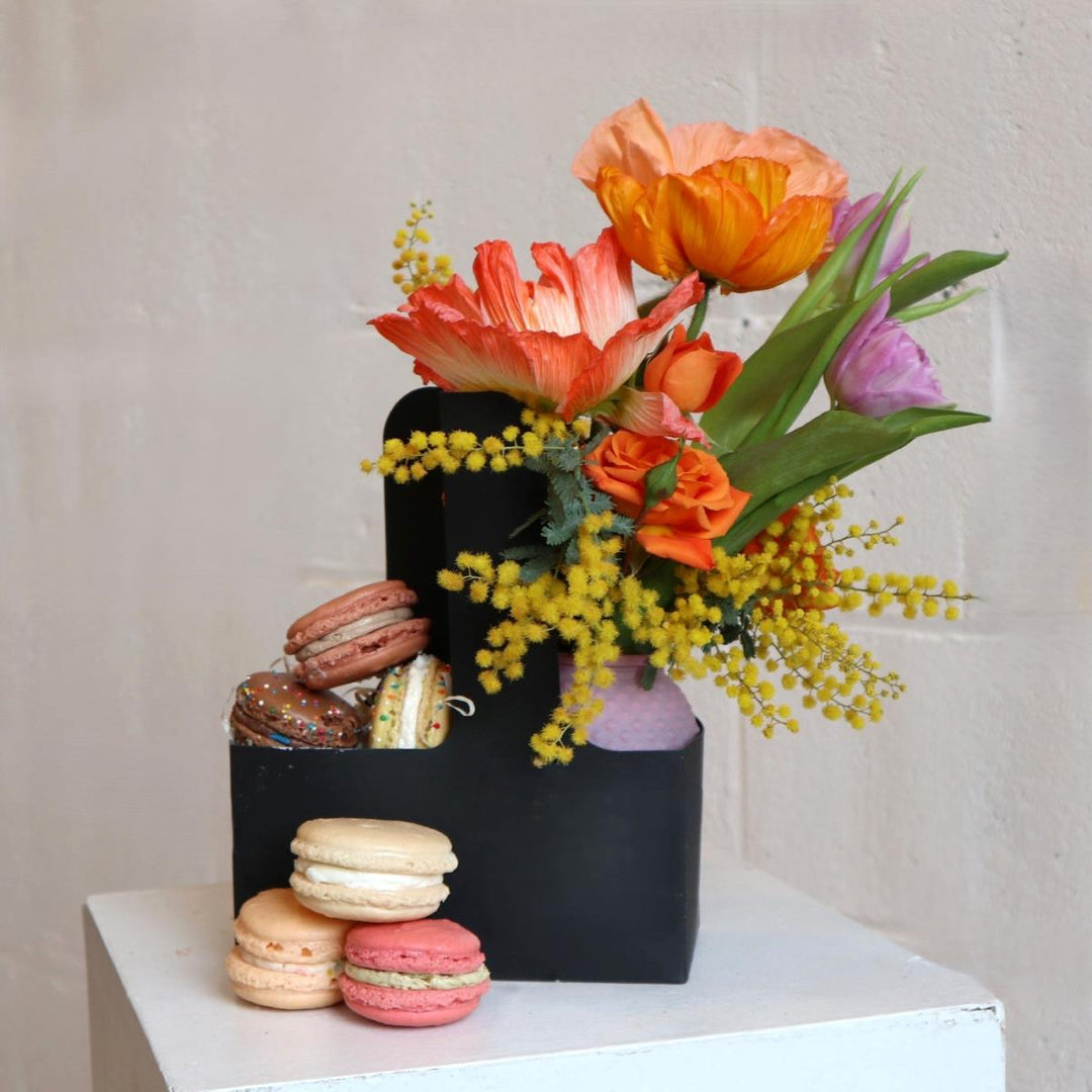 Macaron carrier featuring freshly baked macarons from Scratch Bakeshop on one side and a beautiful floral arrangement from Stacy K on the other